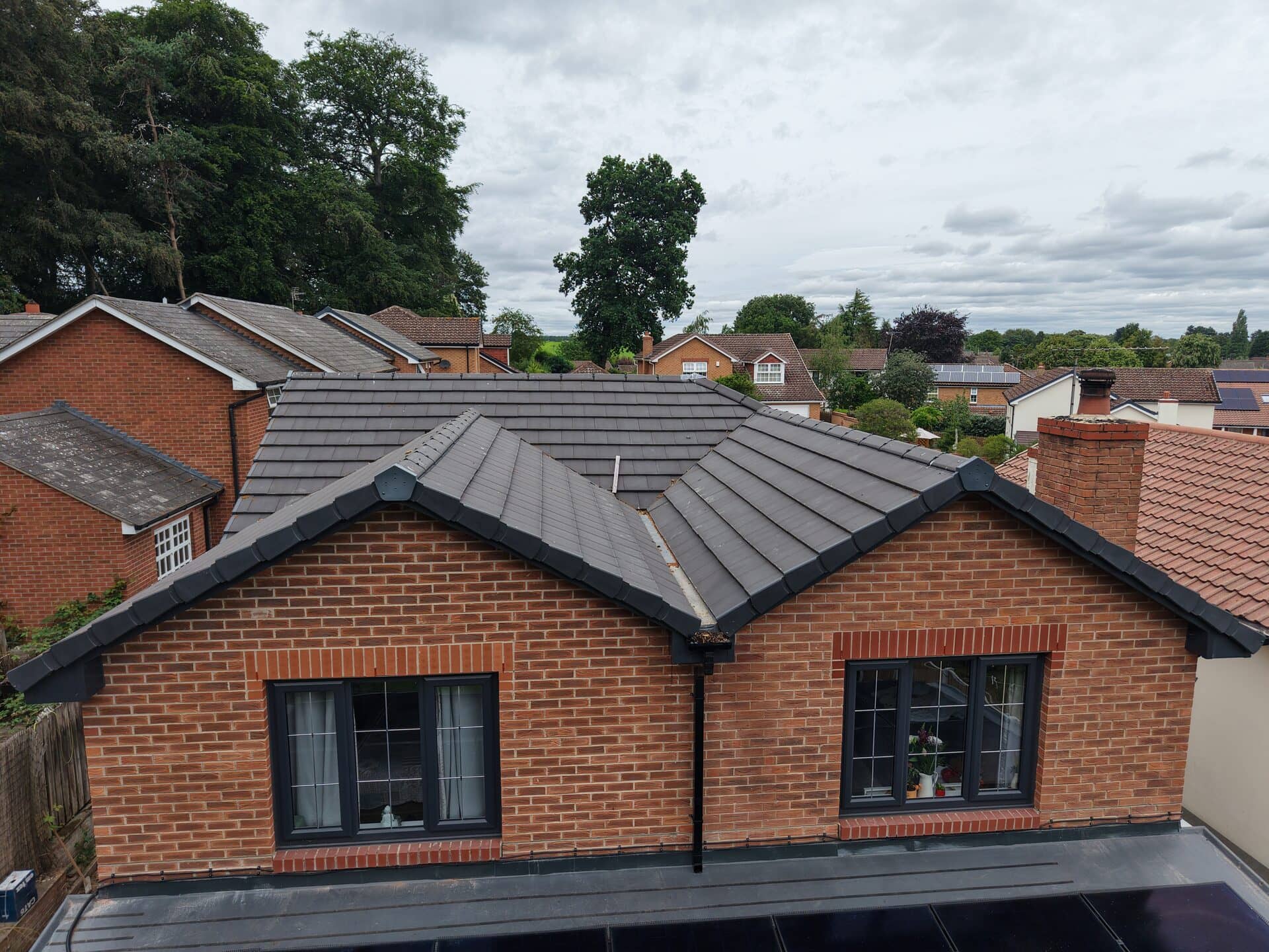 Aerial photo of a brick house among neighbouring homes under a clear sky