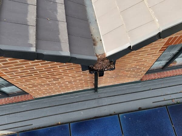 Close aerial detail of guttering running along a tiled roof, useful for spotting blockages.