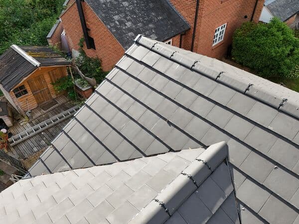 Aerial roof overview showing tiled pitches above a garden and neighbouring access.