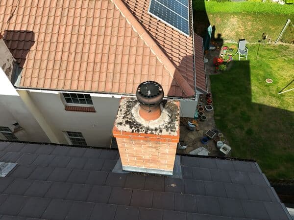 Close aerial view of a chimney, roof tiles and surrounding access areas for inspection or quoting.