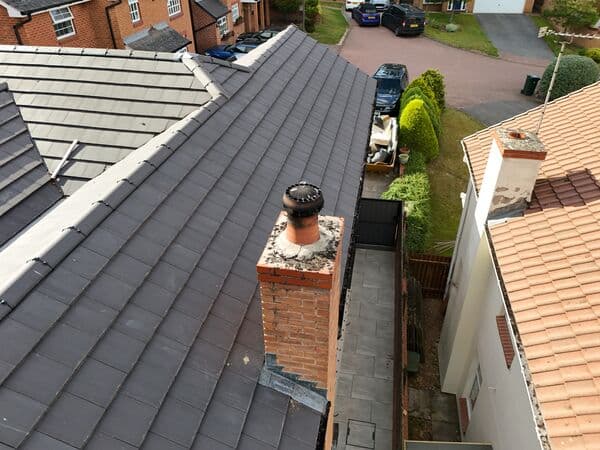 Aerial roof view showing a chimney, tiled roof sections and surrounding access for inspection or quoting.