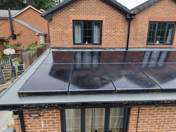 Aerial photo of roof-mounted solar panels and surrounding roof/gutter detail.