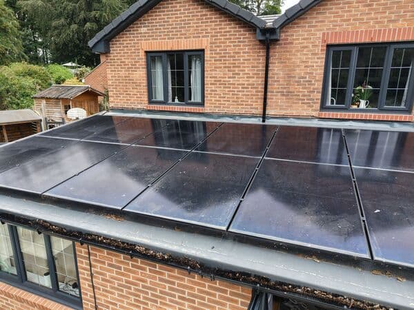 Close aerial photo of solar panels, roof edge and gutter line on a residential property.